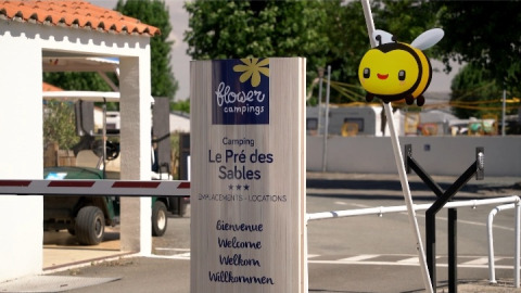 Indgang til Flower Camping Le Pré des Sables med velkomstskilt og en sød bi-dekoration i Pays de la Loire.
