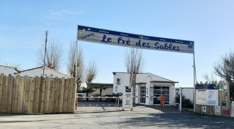 Entrance to Flower Camping Le Pré des Sables holiday park in Pays de la Loire, France, with signs and fencing.