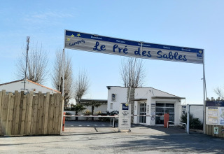 Entrée du Flower Camping Le Pré des Sables, un parc de vacances à Pays de la Loire, France, avec des panneaux visibles.