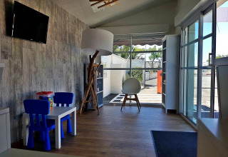 Bright lounge area with children's table and chairs at Flower Camping Le Pré des Sables in France.