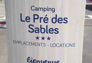 Sign for Flower Camping Le Pré des Sables in Pays de la Loire, France, displaying multilingual greetings.