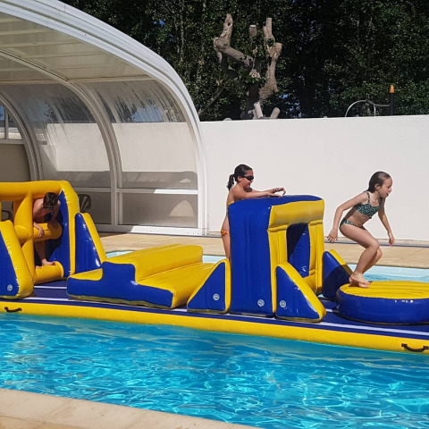 Enfants jouant sur un parcours gonflable aquatique à Flower Camping Le Pré des Sables en Pays de la Loire.