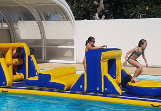 Niños juegan sobre un circuito hinchable en la piscina de Flower Camping Le Pré des Sables en Pays de la Loire.