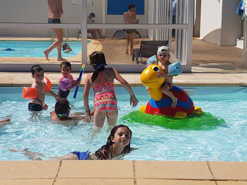 Kinderen spelen en zwemmen in het buitenzwembad bij Flower Camping Le Pré des Sables in Frankrijk.