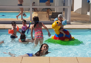 Børn leger og svømmer i en udendørs swimmingpool på Flower Camping Le Pré des Sables i Frankrig.
