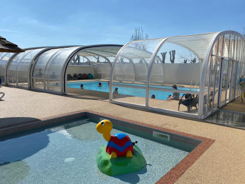 Piscina cubierta y piscina infantil con juguete de tortuga en Flower Camping Le Pré des Sables, Pays de la Loire, Francia.