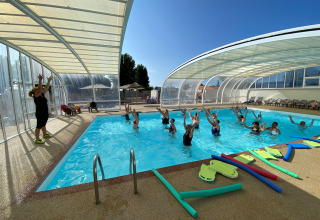 Cours d’aquagym avec moniteur et vacanciers dans la piscine couverte du Flower Camping Le Pré des Sables, France.