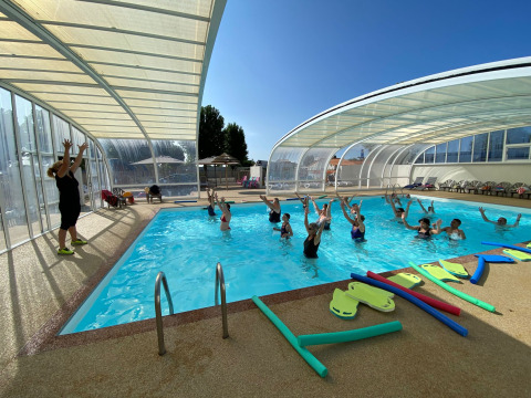 Cours d’aquagym avec moniteur et vacanciers dans la piscine couverte du Flower Camping Le Pré des Sables, France.