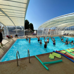Aquafitness class with instructor and guests in the covered pool at Flower Camping Le Pré des Sables, France.