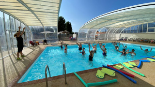 Aquafitness class with instructor and guests in the covered pool at Flower Camping Le Pré des Sables, France.