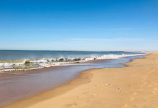 Spiaggia tranquilla con sabbia dorata e onde leggere sotto un cielo terso in Pays de la Loire, Francia.