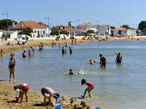 Menschen spielen am Strand und schwimmen im Wasser bei Flower Camping Le Pré des Sables in Frankreich.
