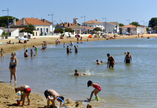 Famiglie si godono la spiaggia e nuotano a Flower Camping Le Pré des Sables, Pays de la Loire, Francia.