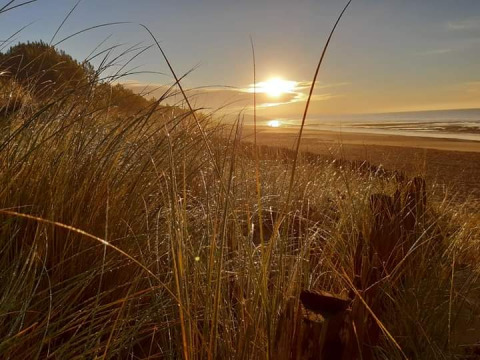 Zonsondergang boven strand en duinen bij Flower Camping Le Pré des Sables in Pays de la Loire, Frankrijk.