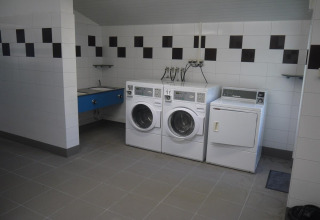 Locale lavanderia con due lavatrici, un'asciugatrice e un lavello in un villaggio vacanze nei Pays de la Loire.