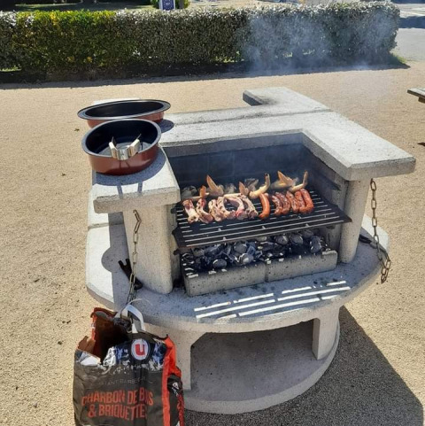 Barbacoa al aire libre con carne y salchichas sobre carbón, día soleado en camping en Pays de la Loire, Francia.