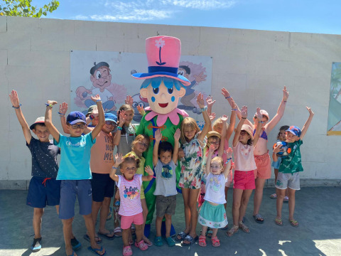 Kinderen poseren vrolijk met een mascotte bij Flower Camping Le Pré des Sables in Pays de la Loire, Frankrijk.
