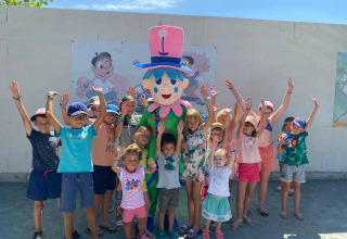 Des enfants entourent une mascotte joyeuse au Flower Camping Le Pré des Sables, Pays de la Loire, France.