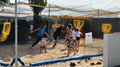 Niños juegan en una zona de arena rodeada de redes en Flower Camping Le Pré des Sables, Pays de la Loire, Francia.