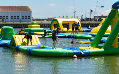 Persone si divertono in un grande parco acquatico gonfiabile al Flower Camping Le Pré des Sables in Pays de la Loire, Francia.