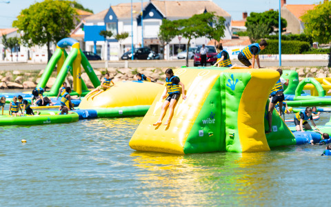 Kids enjoy an inflatable water park at Flower Camping Le Pré des Sables holiday park in Pays de la Loire, France.