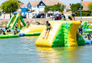 Des enfants jouent dans un parc aquatique gonflable au Flower Camping Le Pré des Sables, Pays de la Loire, France.
