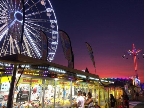 Photo de nuit à la fête foraine avec grande roue et lumières au Flower Camping Le Pré des Sables, France.
