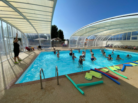 Wassergymnastik mit Teilnehmern und Trainerin im überdachten Pool bei Flower Camping Le Pré des Sables.