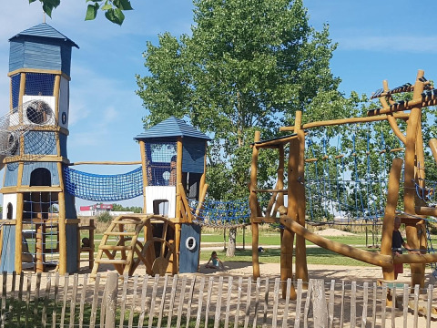 Parco giochi con torri, reti da arrampicata e strutture in legno a Flower Camping Le Pré des Sables, Francia.