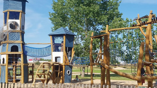 Playground with towers, climbing nets, and wooden structures at Flower Camping Le Pré des Sables, France.