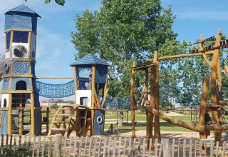 Parco giochi con torri, reti da arrampicata e strutture in legno a Flower Camping Le Pré des Sables, Francia.
