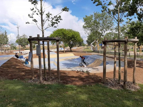 A person rides a BMX bike in a skatepark surrounded by trees at Flower Camping Le Pré des Sables.