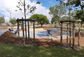 Iemand fietst op een BMX in een skatepark omringd door bomen bij Flower Camping Le Pré des Sables.