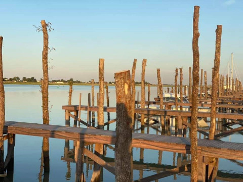 Embarcadero de madera junto al agua tranquila en Flower Camping Le Pré des Sables, Pays de la Loire, Francia.