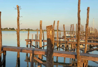 Embarcadero de madera junto al agua tranquila en Flower Camping Le Pré des Sables, Pays de la Loire, Francia.