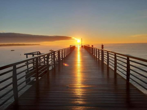 Splendida alba su un molo a L'Aiguillon sur Mer, Pays de la Loire, Francia, con il sole riflesso sull'acqua.