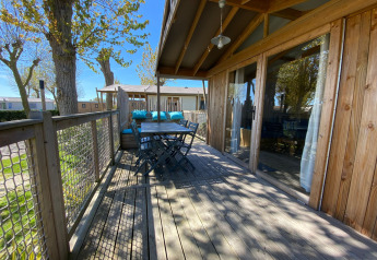 Terraza de madera en Cabane lodge Sweet Flower Premium, Flower Camping Le Pré des Sables, con asientos exteriores.