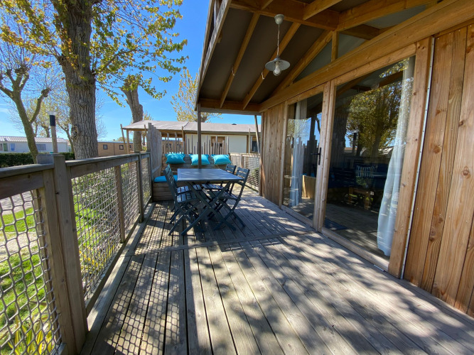 Udendørs terrasse af Cabane lodge Sweet Flower Premium ved Flower Camping Le Pré des Sables, med træmøbler.