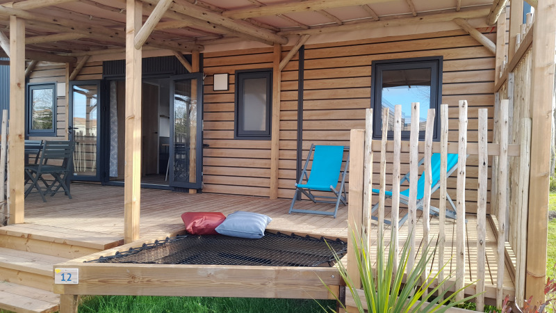 Houten veranda van Stacaravan Premium met blauwe ligstoelen, kussens en een buitenzitje.