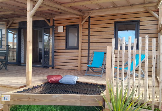 Wooden veranda of a Stacaravan Premium mobile home with blue loungers, cushions, and outdoor seating.