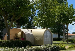 Safari-Zelt Coco Sweet auf Flower Camping Le Pré des Sables, umgeben von Bäumen und sonnigem Himmel.