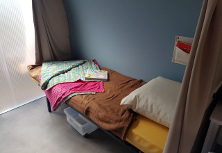 Innenaufnahme eines Einzelbetts in einem Coco Sweet Safarizelt im Flower Camping Le Pré des Sables, Frankreich.