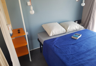 Interieur van een Coco Sweet safaritent bij Flower Camping Le Pré des Sables in Frankrijk met blauw beddengoed.