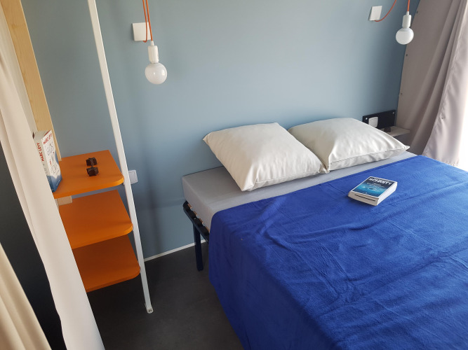 Interieur van een Coco Sweet safaritent bij Flower Camping Le Pré des Sables in Frankrijk met blauw beddengoed.