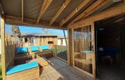 Houten terras met blauwe kussens bij Cabane lodge Sweet Flower Premium, Flower Camping Le Pré des Sables.