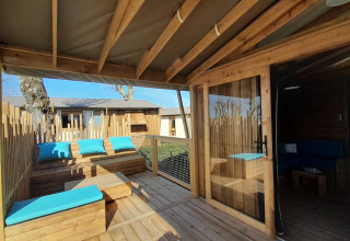 Houten terras met blauwe kussens aan Cabane lodge Sweet Flower Premium, Flower Camping Le Pré des Sables.