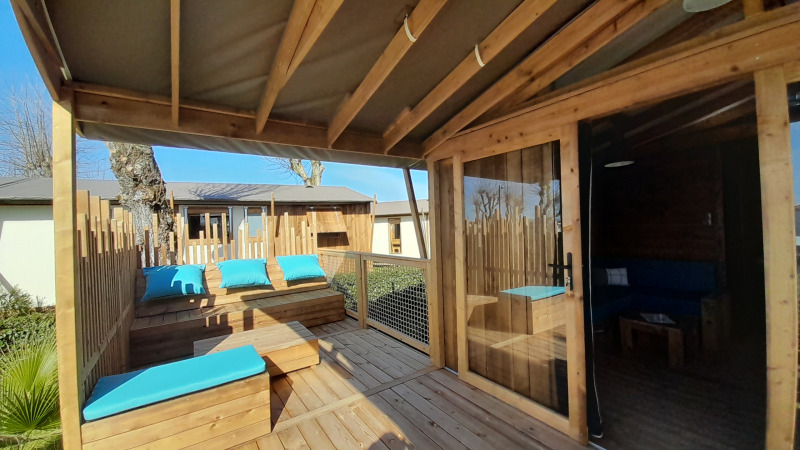 Houten terras met blauwe kussens aan Cabane lodge Sweet Flower Premium, Flower Camping Le Pré des Sables.