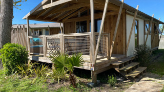 Cabane Lodge Sweet Flower Premium: Chalet aus Holz mit überdachter Terrasse und Garten im Sonnenschein.