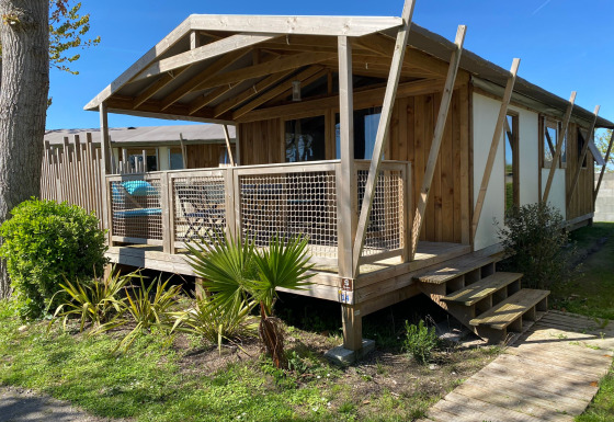 Cabane lodge Sweet Flower Premium chalet met houten terras en tuin op een zonnige dag in het groen.
