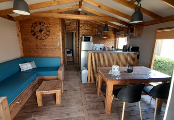 Foto interior de la Cabane lodge Sweet Flower Premium con muebles de madera en Flower Camping Le Pré des Sables, Francia.